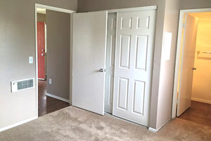 carpeted bedroom facing the tandem bathroom, white closet doors, and bedroom door